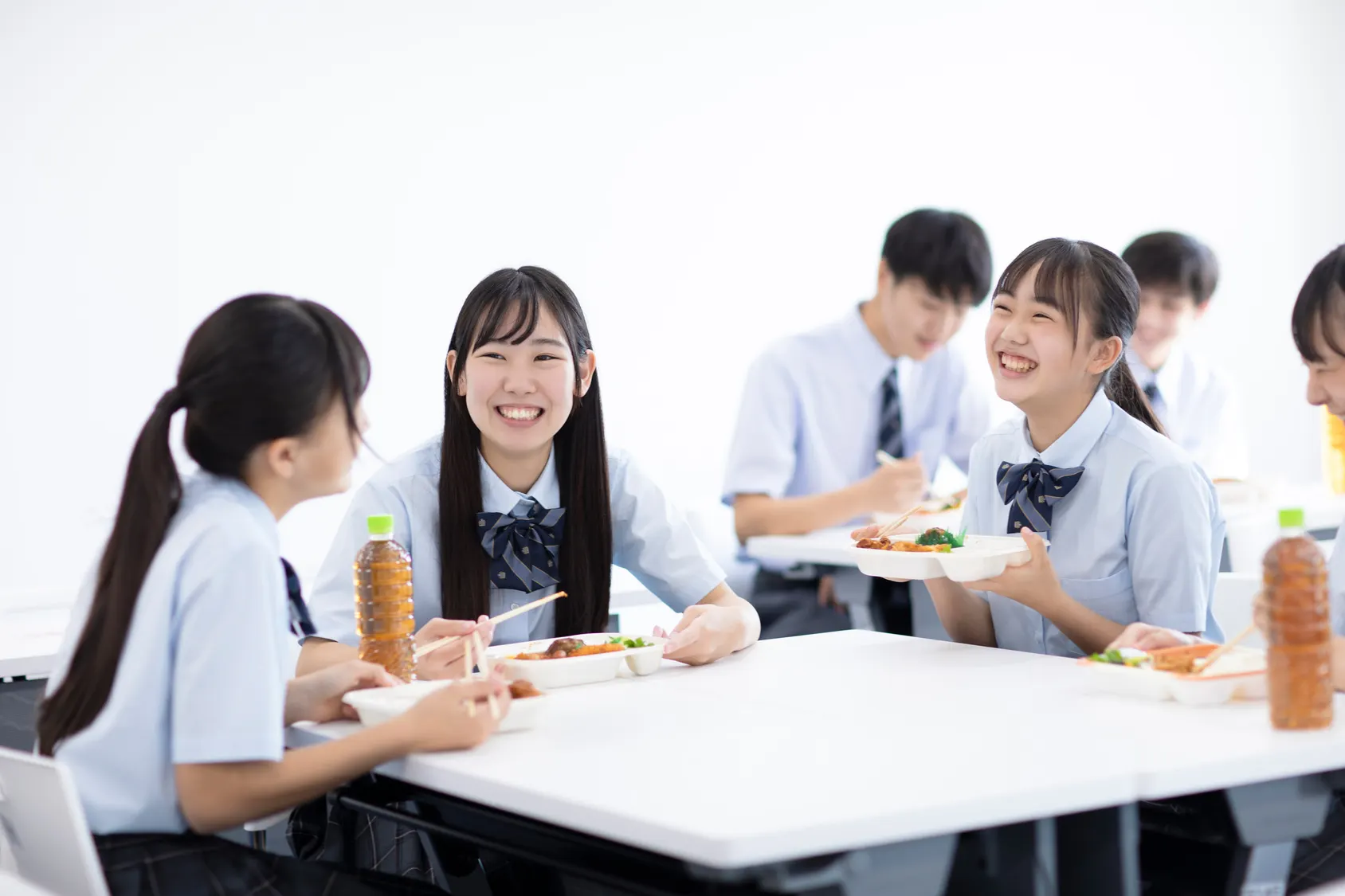 学生たちが教室で楽しそうに昼食を食べる写真